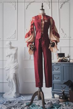 this image showcases a striking victorianinspired outfit against a whitepaneled studio backdrop. the focal point is a mannequin dressed in a rich burgundy suit, featuring a laceup corset, puffedsleeve blouse with delicate floral accents, and tailored trousers.  a vintage side table with decorative items adds to the historical ambiance.
