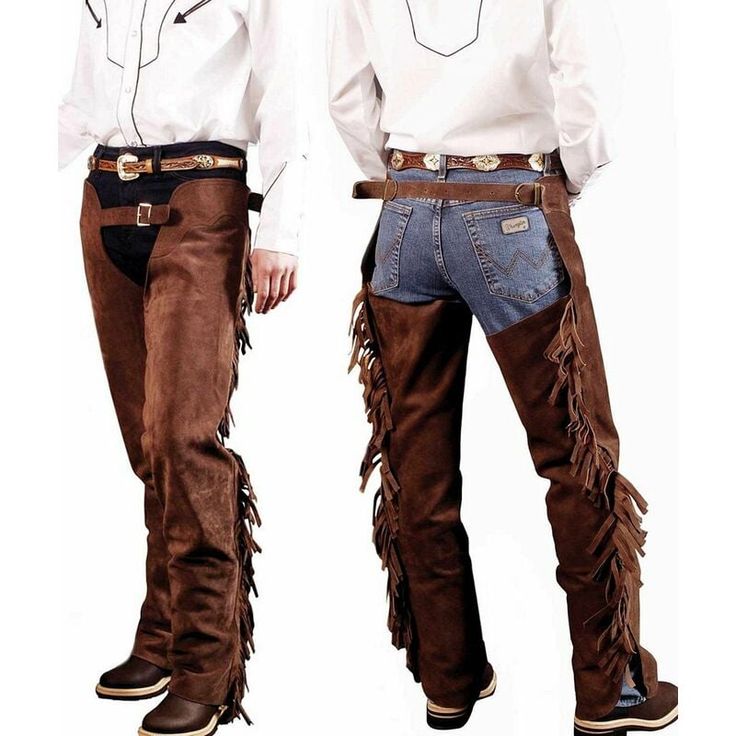 two men are wearing brown leather chaps with fringe. they are both wearing white shirts and jeans. one man is wearing a black belt and the other is wearing a brown belt. the man on the left is wearing brown boots. the man on the right is wearing brown boots. the men are facing different directions. the image is a close up of the men's legs.