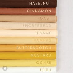 a stack of fabric swatches in various shades of beige, brown, yellow, and orange, each labeled with its color name. the colors from top to bottom are hazelnut, cinnamon, toast, shortbread, sesame, pampas, butterscotch, mustard, ochre, and ecru. the image is taken from a slightly elevated angle, showing the fabric swatches stacked on top of each other. the swatches are arranged in a way that the colors transition from dark to light as you go down the stack.