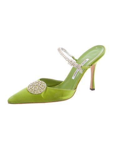 a pair of lime green satin manolo blahnik mules with a pointed toe and a crystalembellished slingback strap. the shoes are highheeled and feature a delicate, elegant design suitable for evening wear or special occasions. the bright green color and sparkling crystals make them stand out.