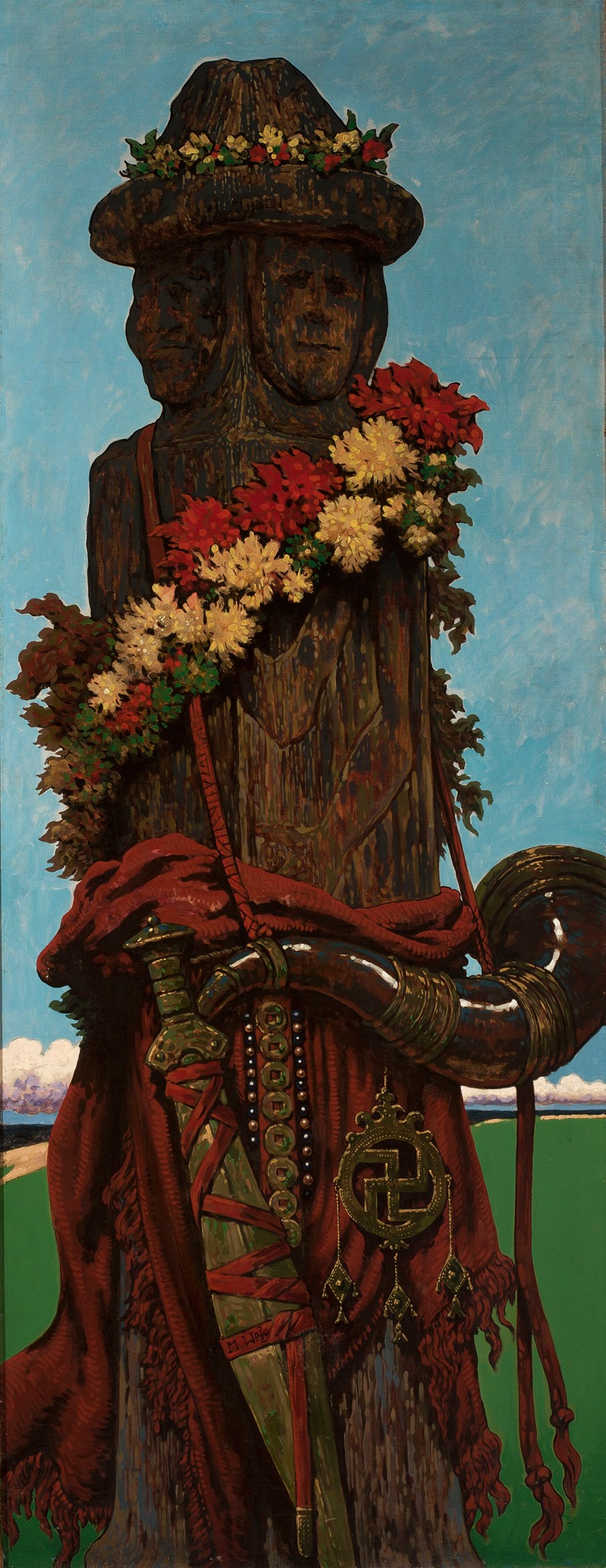 a tall wooden statue with two faces wearing a hat decorated with flowers and several leis around its neck. a red cloth is draped around the base of the statue, and a sword, horn, beads, and pendant hang from it. the background shows a blue sky and a green grass landscape.