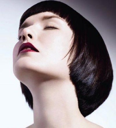 a closeup portrait of a woman with a sleek, dark bob haircut. her head is tilted back slightly, her eyes are closed, and her lips are painted a deep red. the lighting is soft and diffused, highlighting her pale skin and the sharp lines of her haircut.