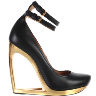 loseup view of a women's black leather wedge heel shoe with a gold platform and a double ankle strap. the shoe has a unique cutout design in the platform.  the style is elegant and fashionable.