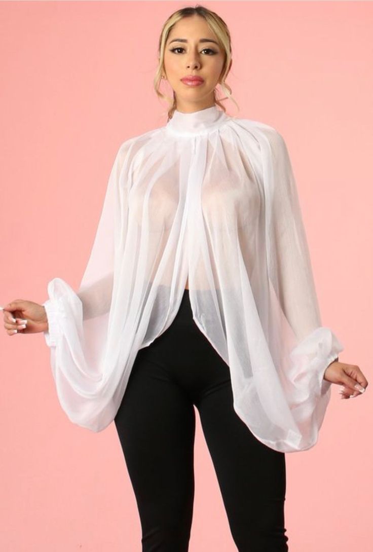 a young woman is standing in front of a light pink background wearing a long sleeve white sheer mesh blouse with ruched details. the blouse has a high neckline and is gathered at the sleeves and waistline. the woman is wearing black leggings and has her hair pulled back from her face.  she's looking directly at the camera.