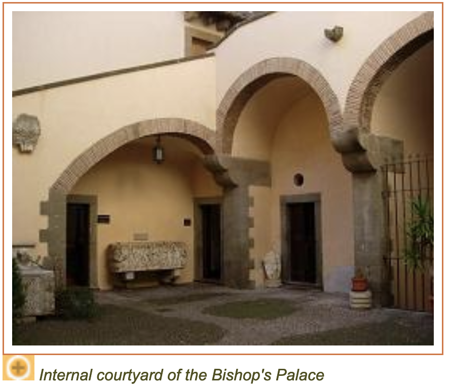the image shows the internal courtyard of the bishop's palace. the courtyard features arches supported by stone columns and several doorways leading into the building. there is brick arch. the building is made of stone and the courtyard also has plants.
