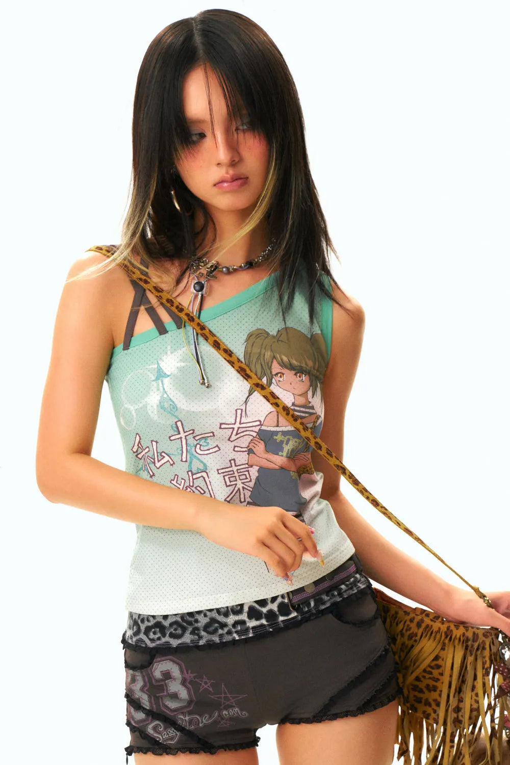 a young asian woman with long black hair styled with bangs is posing in a studio shot against a white background. she is wearing a light teal tank top with an animeinspired design, dark grey shorts with a leopard print detail and lace trim, and a fringed leopardprint handbag. she is also wearing a necklace. her expression is somewhat serious and she is looking slightly down and to the side.