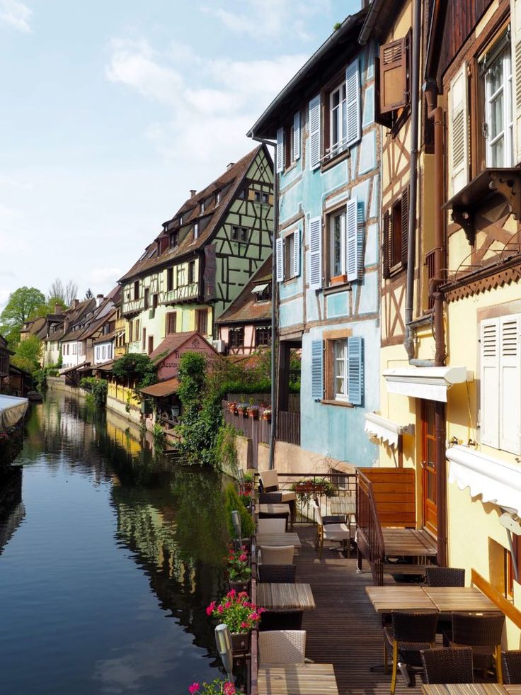 a picturesque view of a canal in a charming european town. the canal is lined with colorful, old buildings, many of which have traditional halftimbered facades. there are boats moored along the canal, and people are enjoying the cafe and restaurant on the waterfront. the scene is bathed in warm sunlight, and the reflection of the buildings in the water is clear and beautiful. the image is a perfect example of the beauty and charm of europe's historic towns.