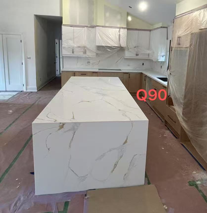 a kitchen under renovation with a large island, cabinets, and marble countertops. the kitchen is still under construction, with the cabinets covered in plastic wrap.