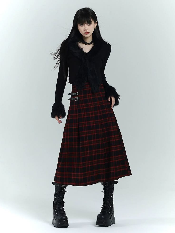 a young woman wearing a black sweater with fur collar and a red plaid skirt. she is also wearing black boots with platform soles and has a black necklace on. she is standing in a white studio setting.