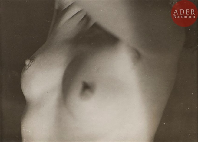 the image is a closeup black and white photograph of a nude female torso. the focus is soft, creating a dreamy, almost abstract effect. the subject's hands are partially visible, gently touching their chest. the lighting plays with shadows and highlights, emphasizing the curves and texture of the body. the overall tone is sensual and intimate, with a hint of vintage aesthetic. the photograph displays the artistic style of a classic approach to nude photography. a stamp of "ader nordmann" is present on the image.