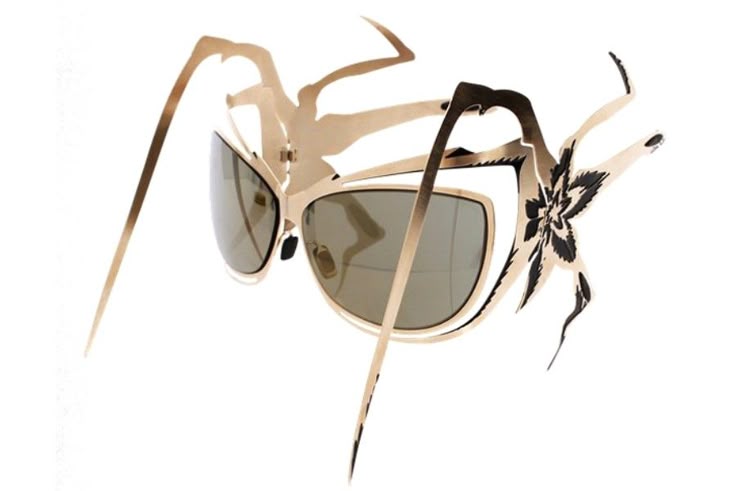 a pair of gold sunglasses with an intricate design. the frames are gold, and the lenses are tinted. the design features a floral pattern on the side.