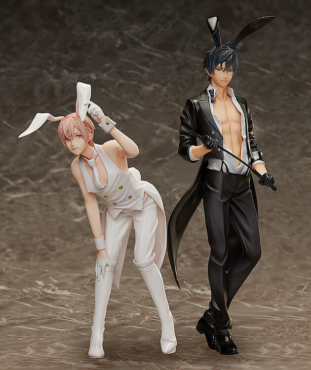 the image shows two animestyle figurines. one figurine is a male character dressed in a white bunny waiter/butler costume, complete with bunny ears and long white gloves. his posture is slightly hunched over. the second figurine is a male character in a black tuxedo, also with bunny ears,  holding a riding crop or whip. he has a more confident, upright posture. both figurines are standing on a marblelike surface. the overall style suggests they are collectible figures from a manga or anime.  the figures are sharply detailed and high quality.