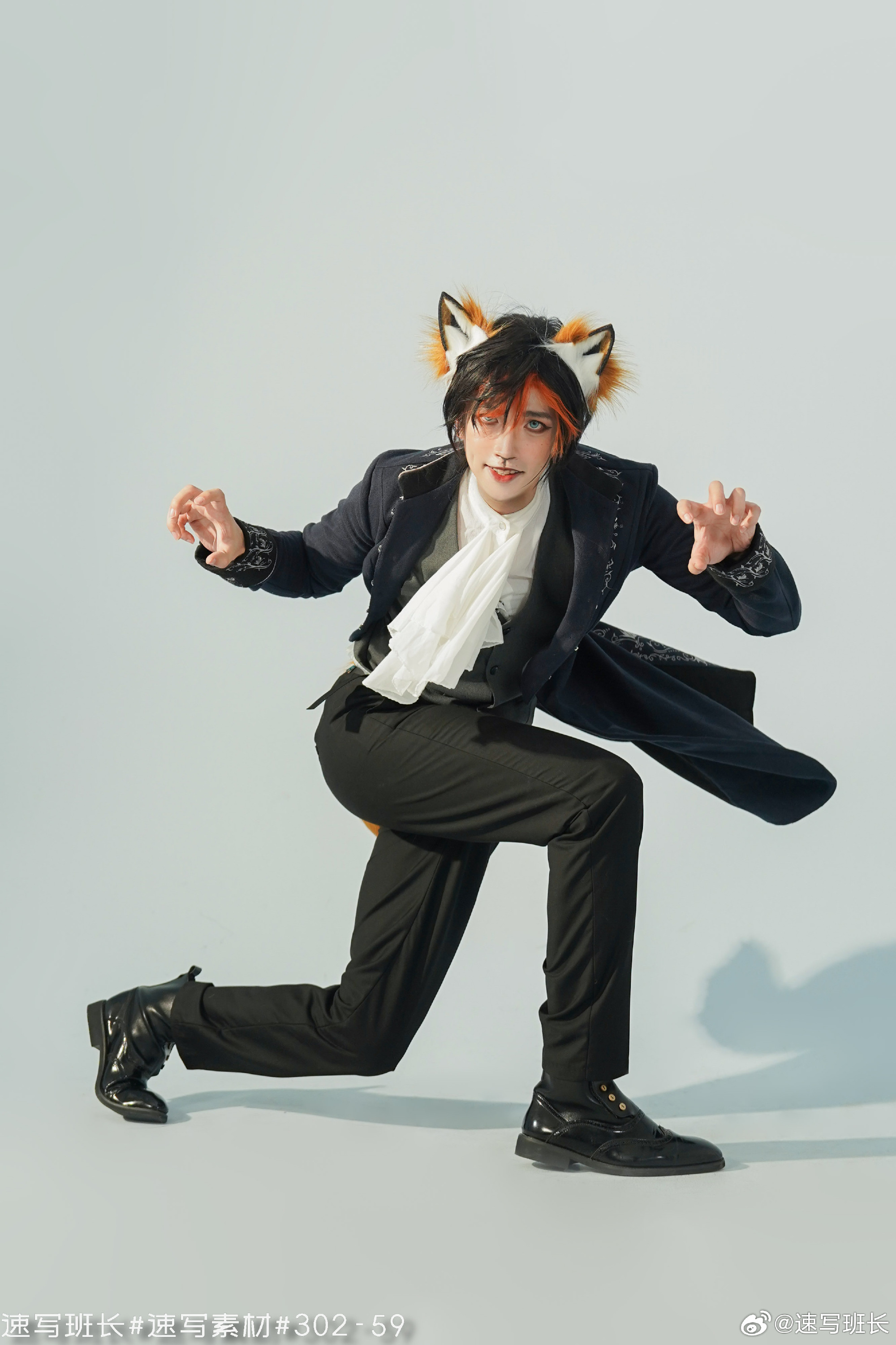 a man in a black suit with fox ears and tail poses against a blue background.  he is wearing a white scarf and has theatrical makeup on.  the lighting is soft and artificial, giving the image a studiolike feel.  the perspective is low, giving the viewer the impression that they are looking up at the subject.