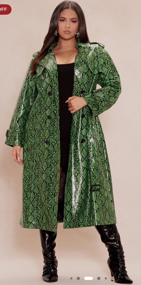 a woman in a green snakeskin trench coat over a black dress, paired with kneehigh black boots.