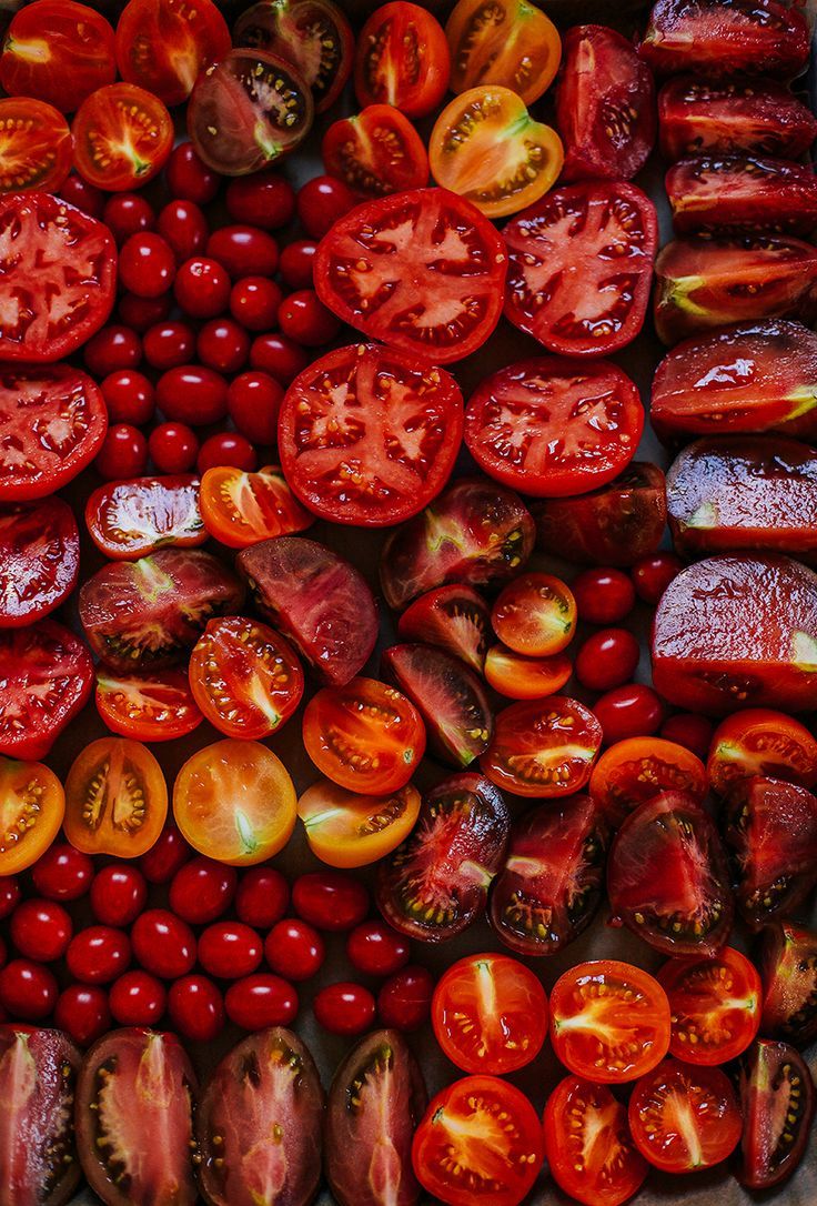 the image showcases a vibrant assortment of tomatoes, including red and yellow varieties, halved large tomatoes, sliced mediumsized tomatoes, and clusters of cherry tomatoes. they are arranged closely together, creating a colorful and appealing display of fresh, healthy vegetables.
