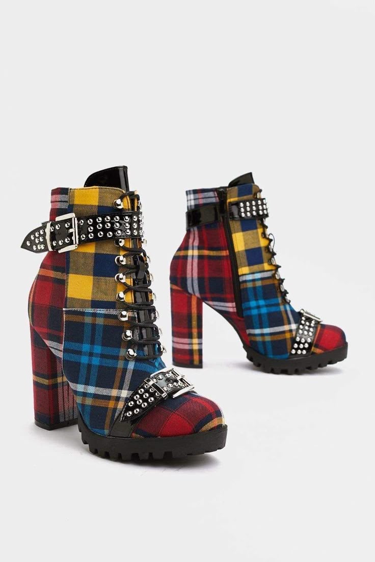 two highheeled boots stand on a white background. the boots are laceup style and covered in a plaid pattern in red, blue, and yellow. they have studded buckles.