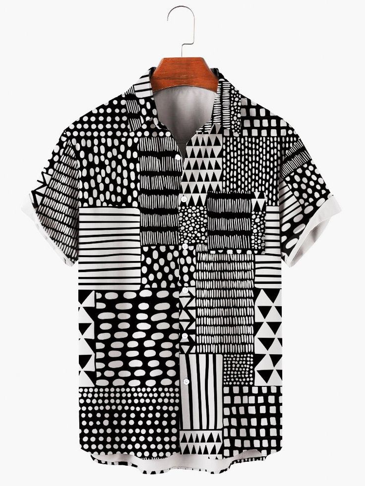 a black and white shortsleeved buttondown shirt hangs from a wooden hanger. the shirt has a repeating pattern of various geometric shapes, including dots, squares, triangles, and lines. the background is plain white.
