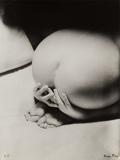 the image is a black and white photograph by man ray, titled "e.a." it is a closeup shot of a nude woman's buttocks and hands, with her feet visible at the bottom. the woman's body is softly lit, creating a dramatic contrast between light and shadow. the hands are gently resting on the buttocks, and the overall composition is both sensual and abstract. the photograph is signed by man ray in the bottom right corner, with "e.a." in the bottom left, possibly indicating an edition number. the texture of the skin is visible and the overall mood is one of quiet intimacy and artistic exploration of the female form.