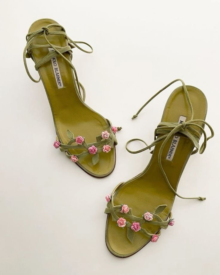 a pair of green manolo blahnik highheeled sandals with pink rose embellishments. the sandals have green straps and leather soles.