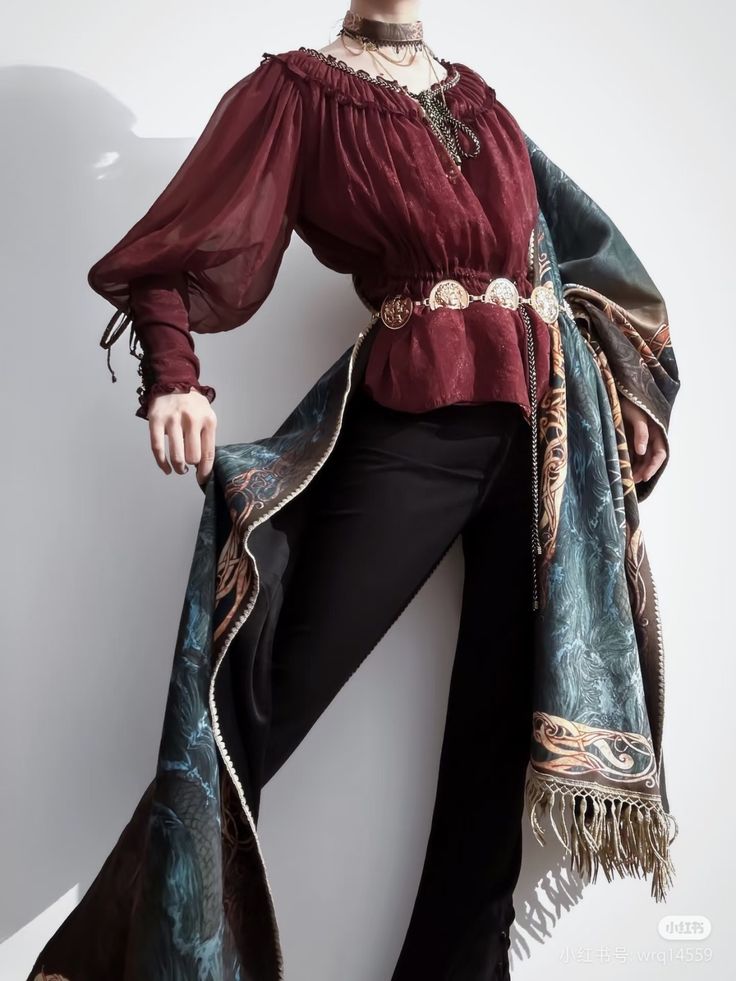 a woman is posing in a maroon blouse with voluminous sleeves, black pants, and a patterned shawl draped over her side. she accessorizes with multiple necklaces, a choker, and a decorative gold belt.