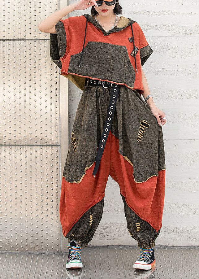 he image shows a woman wearing a stylish twopiece outfit. the outfit consists of an oversized cropped hoodie with a patchwork design in orange and grey, and matching harem pants with distressed denim details.  the pants are also a patchwork design with orange and grey sections. the woman is wearing hightop sneakers and sunglasses, and the overall style is casual and streetwearinspired. the setting appears to be an urban outdoor environment.