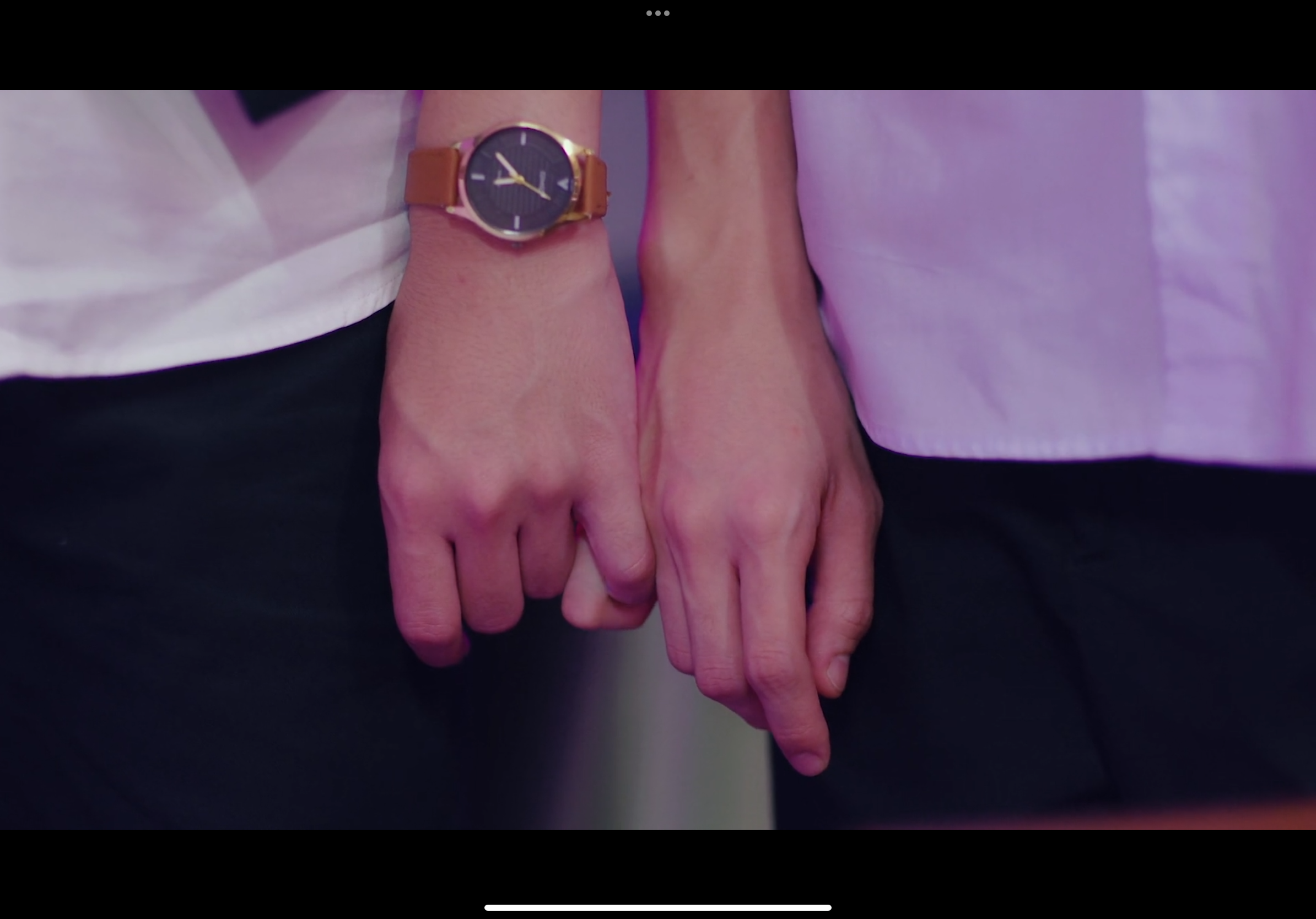 the image shows a closeup of two people holding hands, their arms sidebyside. the person on the left is wearing a brown watch. the background is a blurry purple hue, suggesting an indoor setting with artificial lighting. the overall atmosphere evokes feelings of love, connection, and intimacy.