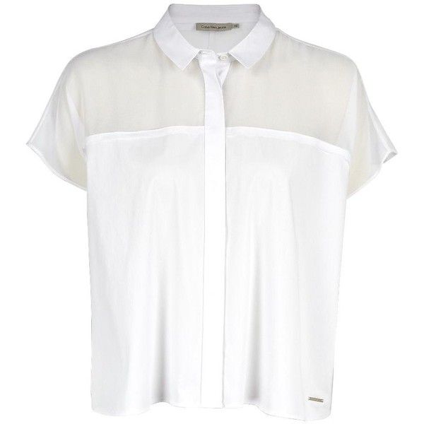 a white short sleeve collared shirt with a transparent panel over the shoulders. the shirt is buttoned up and the sleeves are rolled up. the model is wearing the shirt with a casual look, but it could also be dressed up for a more formal occasion.