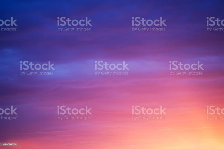 the image is a beautiful gradient of colors in the sky, transitioning from a dark blue at the top to a bright orange at the bottom. it looks like a sunset or sunrise with horizontal layers of clouds blending together. the colors include shades of blue, purple, pink, orange, and yellow, creating a vibrant and peaceful scene.