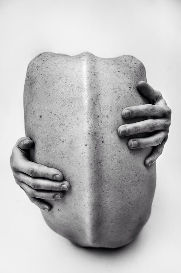 the image is a striking black and white photograph of a person's back, viewed from behind.  the subject's arms are wrapped around their torso, their hands gently grasping their back. the skin texture is clearly visible, showing freckles and the natural contours of the back. the overall impression is one of selfreflection, vulnerability, and a sense of introspection. the composition is simple and minimalist, emphasizing the form and texture of the body. the lighting and contrast enhance the dramatic effect of the grayscale image.