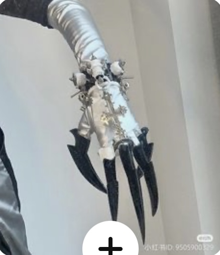 the image shows a closeup of a person's hand wearing an elaborate silver glove with black claws. the glove is adorned with intricate details, including crosses and what appear to be small skulls. the claws are long and sharp, extending from the fingertips. the overall aesthetic suggests a gothic or fantasyinspired costume.