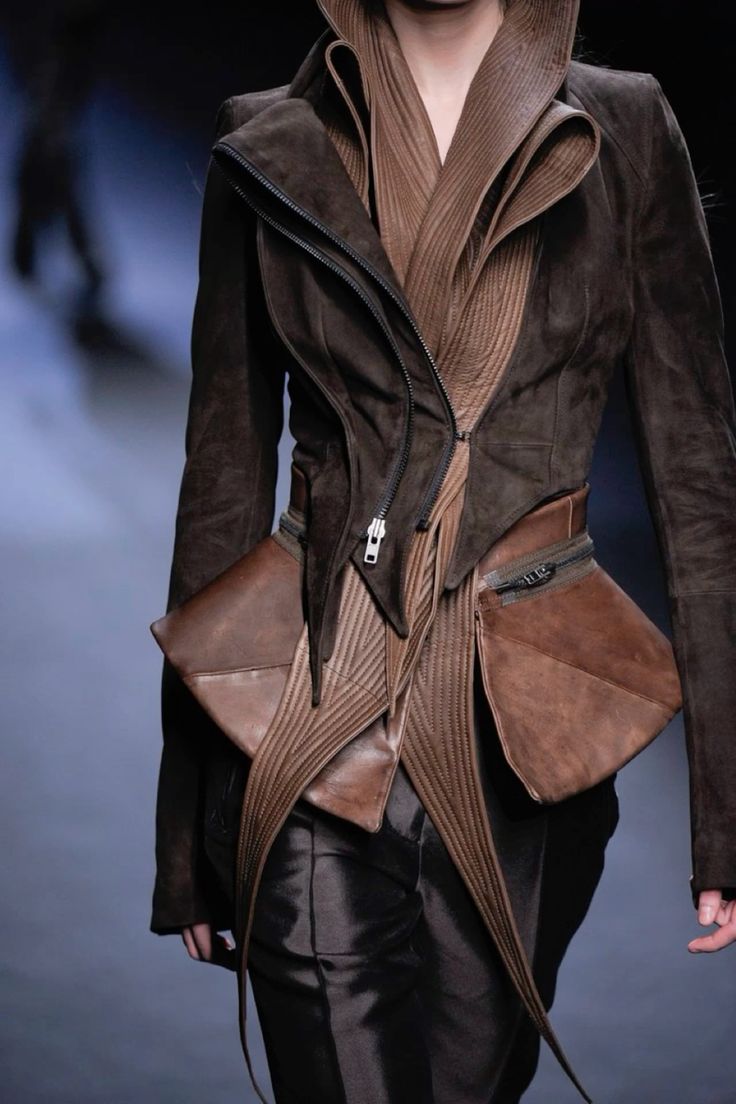 a fashion model showcasing an avantgarde leather jacket, constructed in a unique and complex layering style. the jacket, featuring a brown leather construction, is designed with intricate folds and layers that create a dramatic and artistic silhouette. the model, standing on a runway, embodies the haute couture spirit of the garment, exuding elegance and a captivating sense of style.