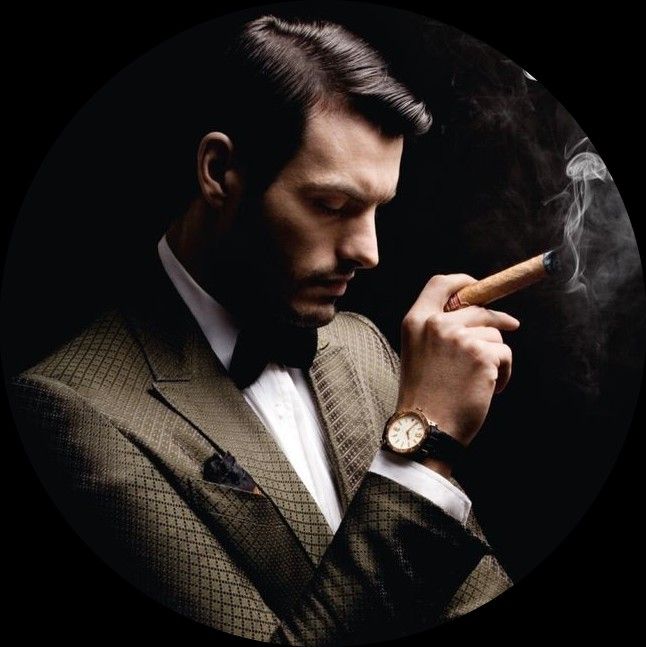 a man in a suit and bow tie is smoking a cigar. he is looking down at the cigar, and there is smoke coming from it. he is wearing a watch on his left wrist. the image is in black and white.