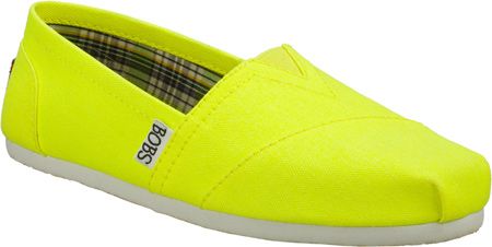 a closeup studio shot features a bright yellow skechers bobs slipon shoe. the shoe has a simple design, with a canvas exterior and a lightcolored sole. the interior is lined with a plaid fabric. the "bobs" logo is visible on the side of the shoe.