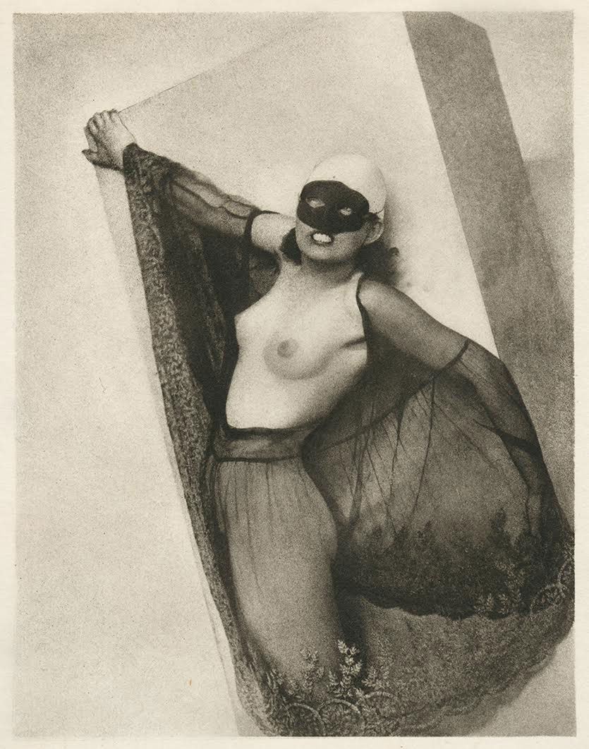 a black and white photograph from the 1920s, possibly art deco in style, shows a woman partially nude and wearing a black eye mask. she is draped in sheer dark fabric, her body partly visible.  her pose is languid and suggestive, leaning against a lightcolored, rectangular object. the overall mood is both mysterious and elegant. the photograph's style uses strong contrasts of light and shadow, creating a graphic and impactful image.