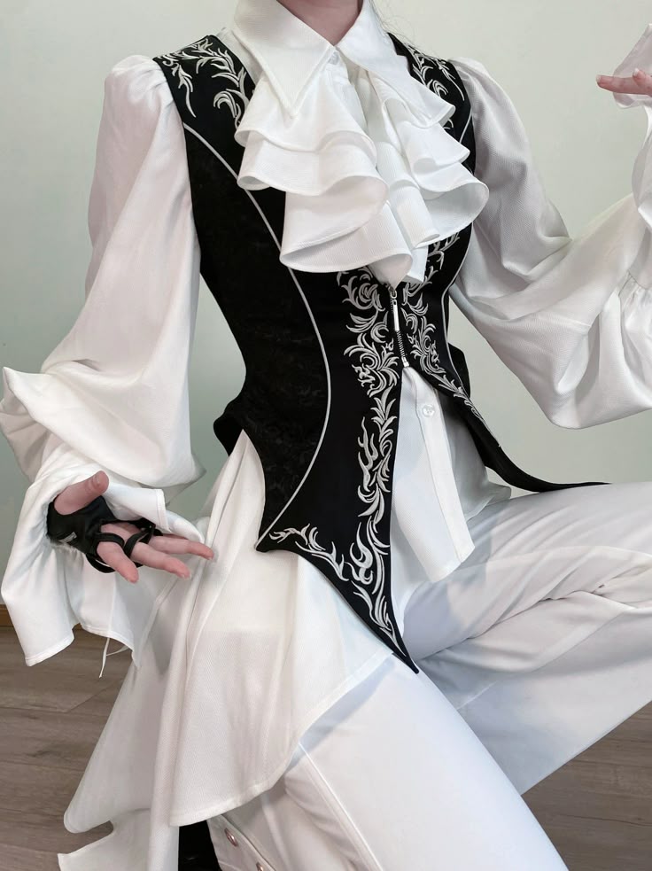 an image of a person wearing a white collared shirt with layered frills at the front, paired with a black vest embroidered with white details. the vest is tailored and long, extending beyond the waist. the outfit includes white pants and fingerless gloves.