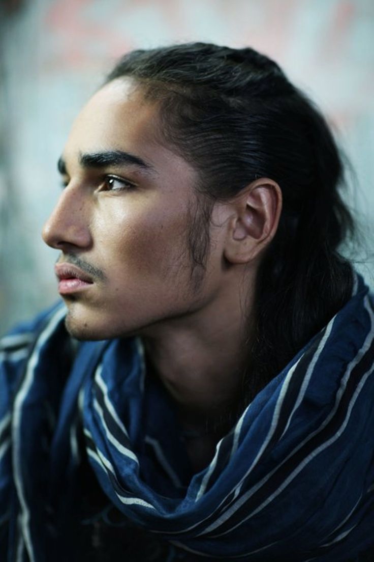 a sideview portrait of a man with long, dark hair, wearing a blue scarf with white stripes. he has facial hair including a mustache. the man is looking to the left with a serious or pensive expression.