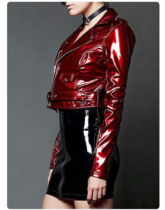 a woman is wearing a red patent leather jacket and a black patent leather skirt. she's posing for the camera, and the outfit is looking very stylish.