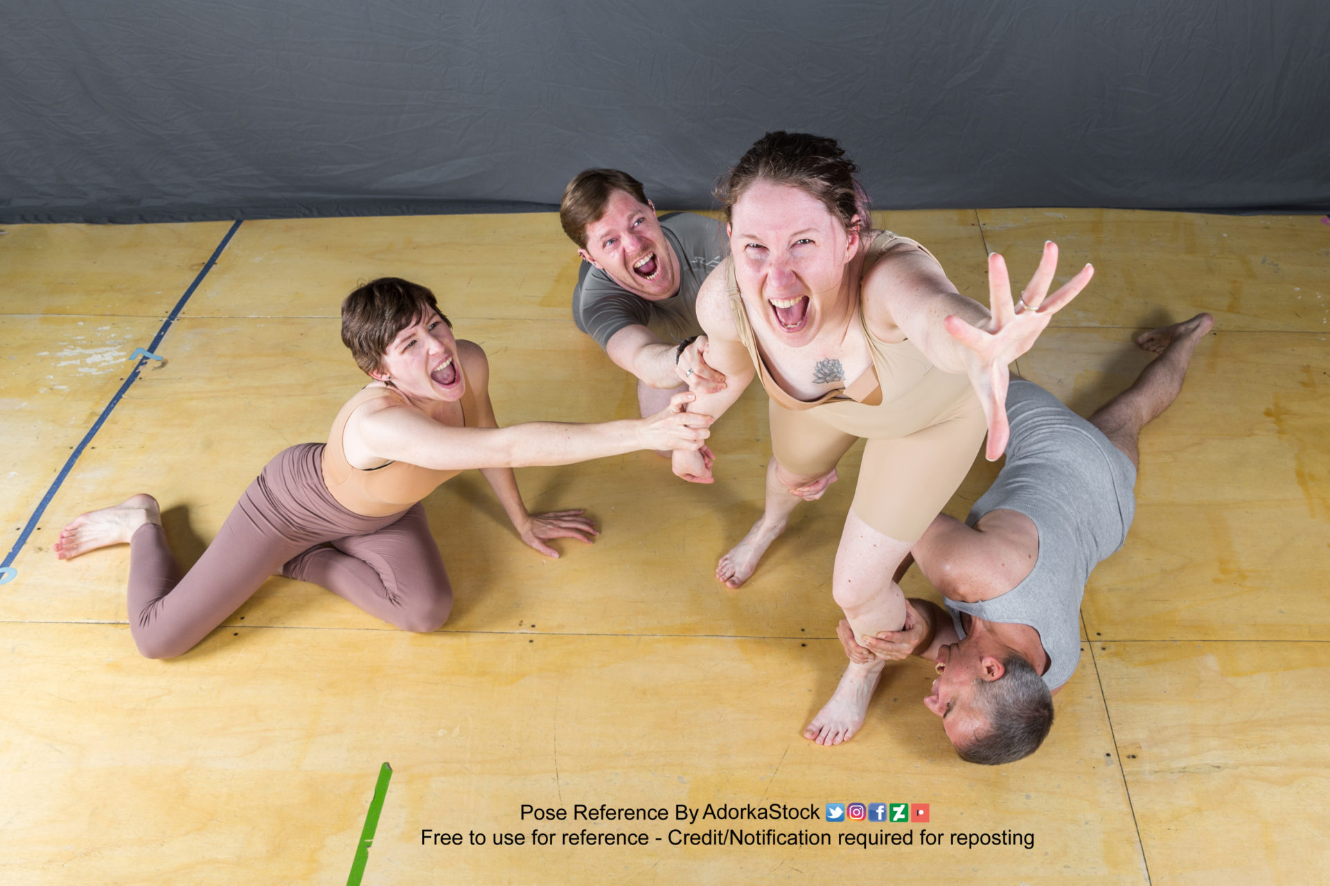 this is a photo of three people posing. the woman on the left is sitting on the floor.  the woman on the right is standing, leaning forward with her right hand outstretched.  she is looking at the camera and yelling. the man in the middle is lying on the floor, looking at the camera and smiling.   the three friends appear to be having fun and  posing for a reference photo.