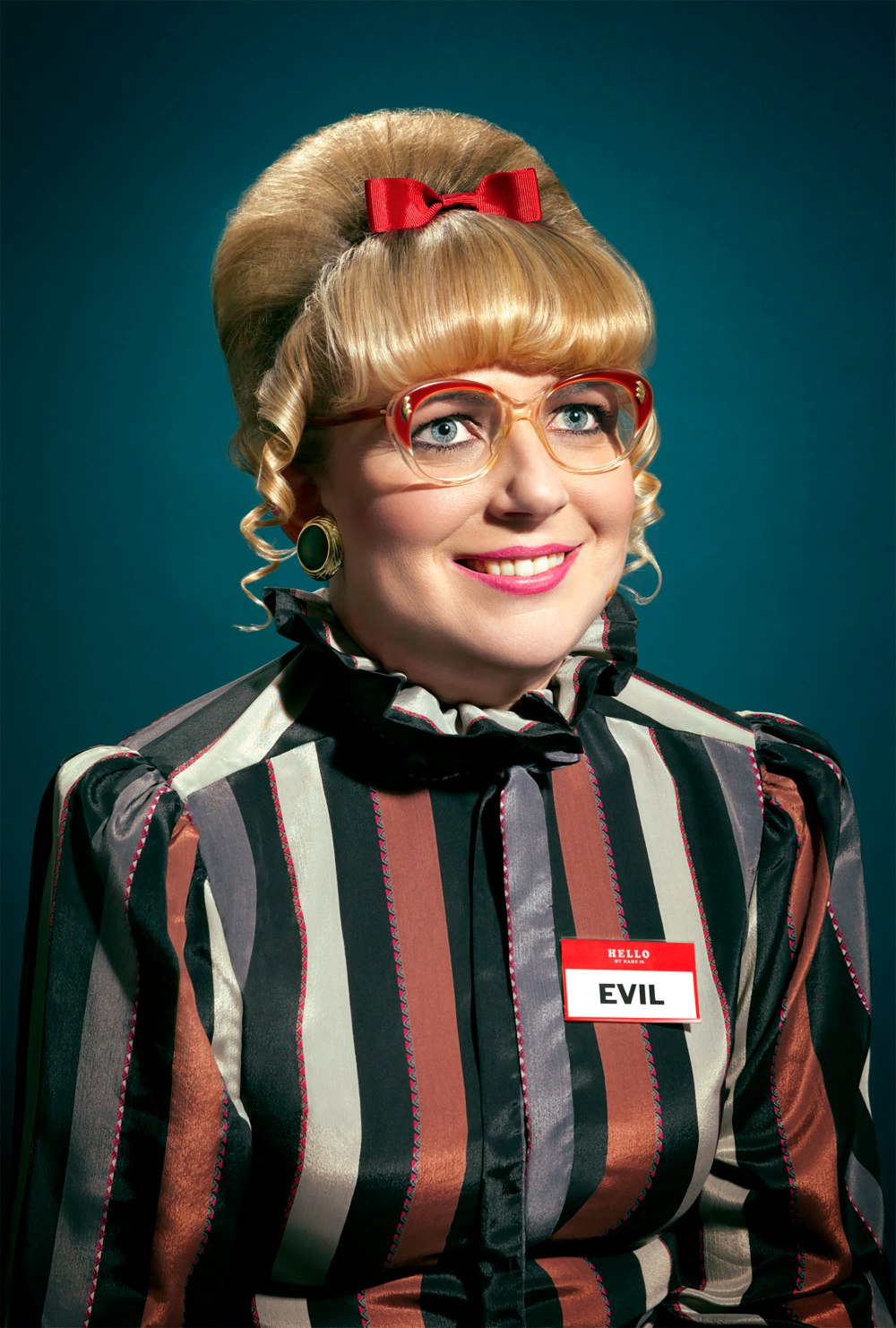 closeup portrait of a woman with a 1960s beehive hairstyle, wearing redrimmed glasses, a red bow, and a striped blouse. she has a name tag that reads "evil." the background is a dark teal color. the overall style is retro and slightly humorous.
