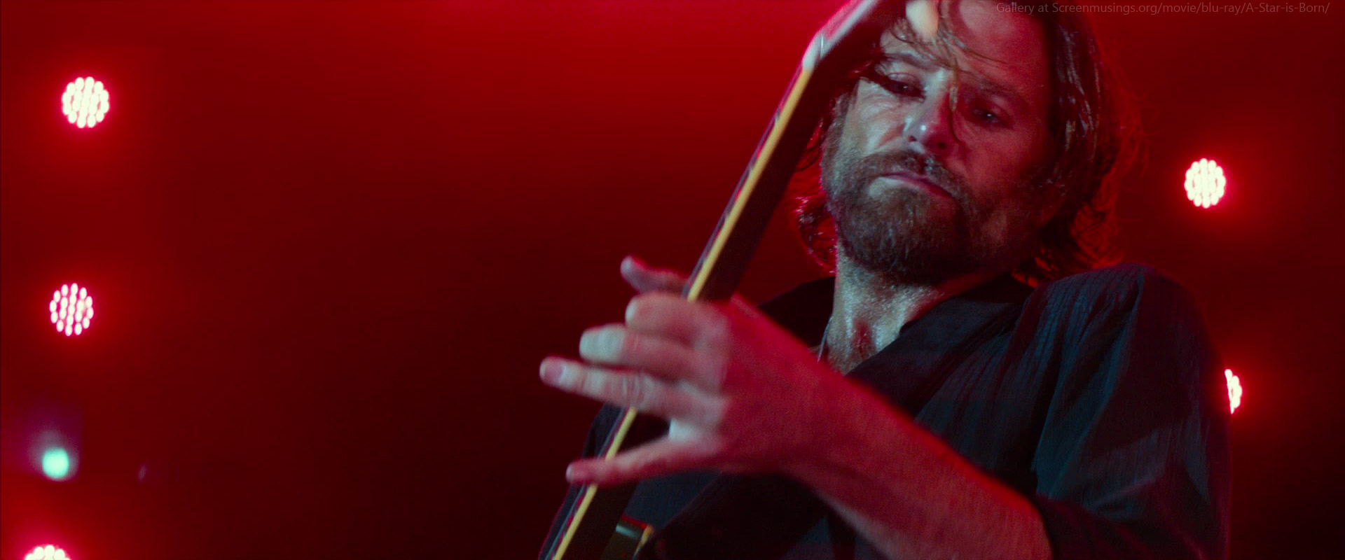 a closeup shot of a male musician passionately playing an electric guitar on a stage bathed in red light. he is sweating, emphasizing the energy of his performance. his expression is serious and focused.  the red stage lights create a dramatic atmosphere.