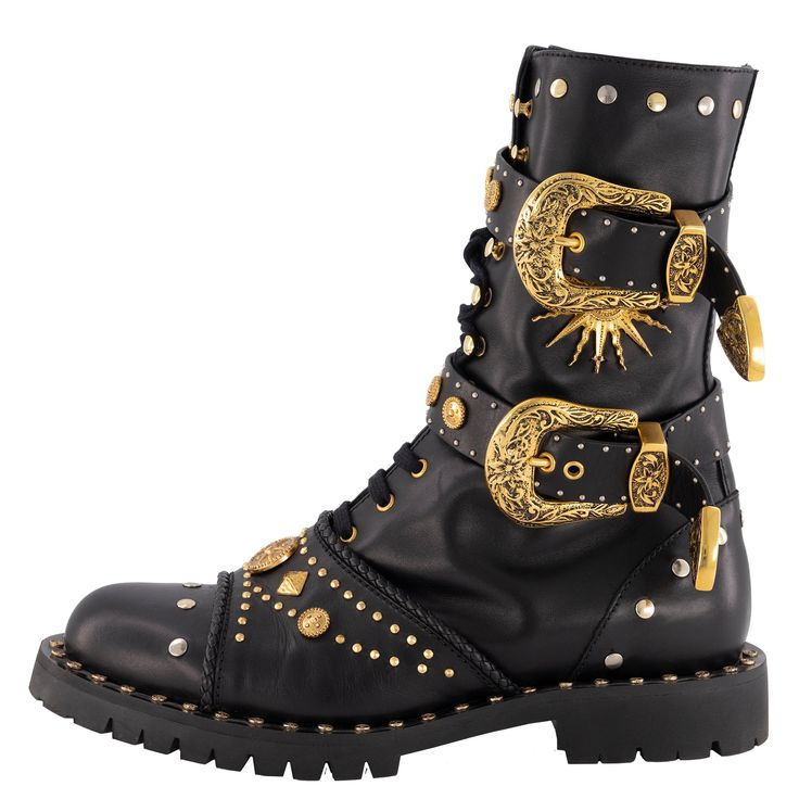 the image showcases a single black leather boot, prominently featuring large gold ornate buckles and numerous metallic studs. the boot is a hightop style, resembling a combat or western boot, with laces visible. the gold detailing is intricate and eyecatching. the boot is presented on a white background, offering a clear and detailed view.  the style is bold and luxurious.