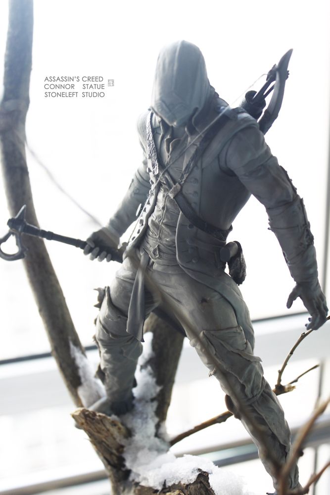 a grayscale image featuring a prototype statue of connor from the video game "assassin's creed." the statue captures a dynamic pose of the character perched on a tree branch, armed with his signature weapons. the intricate details of the character's attire and weaponry are visible, showcasing the craftsmanship of the sculpture.