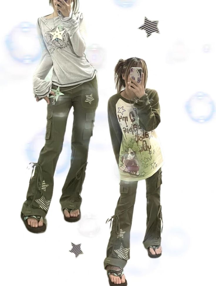 the image shows two models showcasing different outfits.  both outfits feature olive green cargo pants with flare legs and star details. the first model wears a light grey, longsleeved shirt with a subtle graphic design, while the second model wears a light beige, longsleeved shirt with a more prominent cartoon graphic print. both models are wearing similar shoes. the background is white with decorative star shapes. the overall style is a blend of streetwear, alternative, and possibly japanese fashion influences.