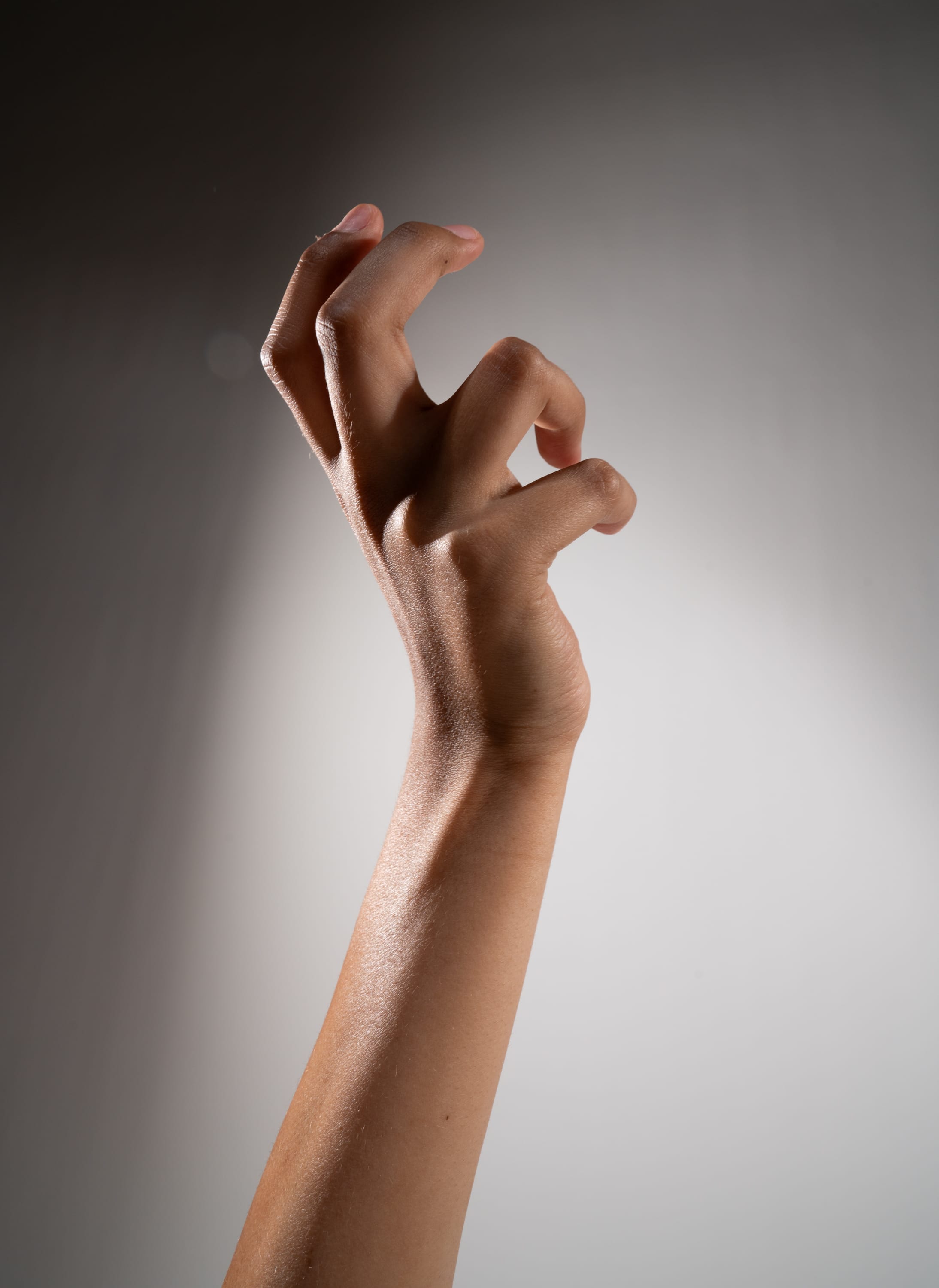 a closeup of a hand with its fingers curled inward against a gray background.
