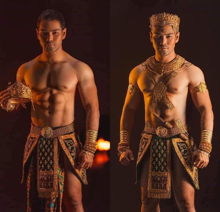 a man in a gold costume with a gold crown, holding a smaller crown in his left hand, stands and stares directly at the camera. he is shirtless and muscular. the background is dark with some highlights of light in the background. he looks to be posing for a portrait and maybe part of a play or performance.