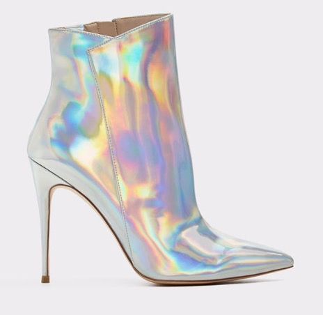 the image shows a pair of women's iridescent silver ankle boots.  the boots are made of a holographic material that shifts color in the light, displaying shades of silver, blue, pink, and purple. they feature a pointed toe and a very high stiletto heel.  the boots are presented against a plain white background, highlighting the shoes' design and texture.