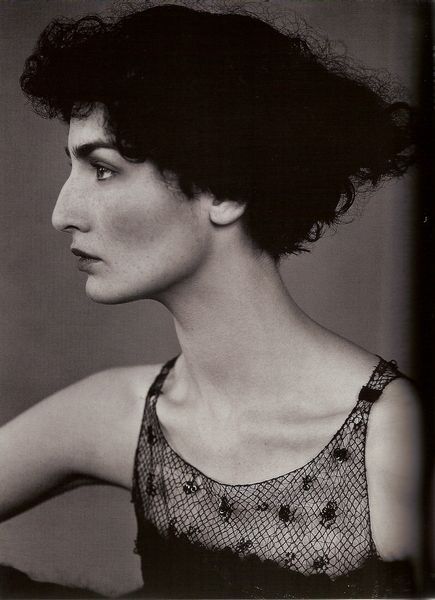 a black and white portrait of a woman in profile, showcasing her elegant features and vintagestyle appearance. she is wearing a lace dress and her hair is styled in a retro fashion. the closeup shot highlights her face, neck, shoulder, and arm.