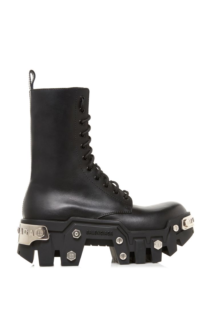 the image showcases a single balenciaga black leather combat boot.  the boot features a hightop design with laceup closures, a chunky lug sole, and prominent silver metal accents along the sole and heel. the leather appears smooth and highquality. the overall style is rugged and edgy, suggesting a fashionable, contemporary design.  the boot is presented on a white background, allowing for a clear view of its details.