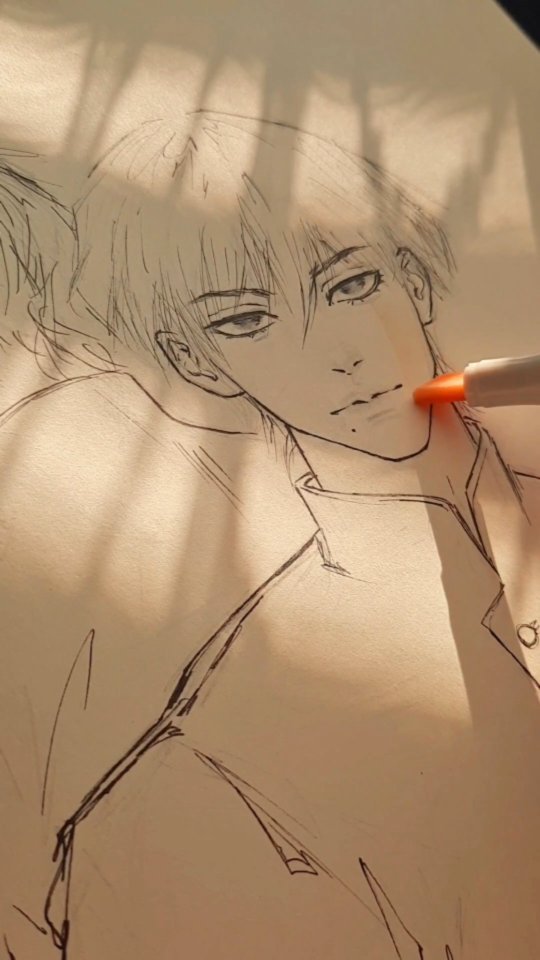 a closeup shot of an artist's hand sketching an animestyle male character's face and upper body. the drawing is in progress, with visible pencil and ink lines. the character has short, slightly messy hair and is depicted with soft, expressive eyes. the setting appears to be indoors, with sunlight casting shadows on the paper and the character's face. the artist is using a lightcolored pen or marker. the overall style of the artwork is delicate and captures a sense of serenity.
