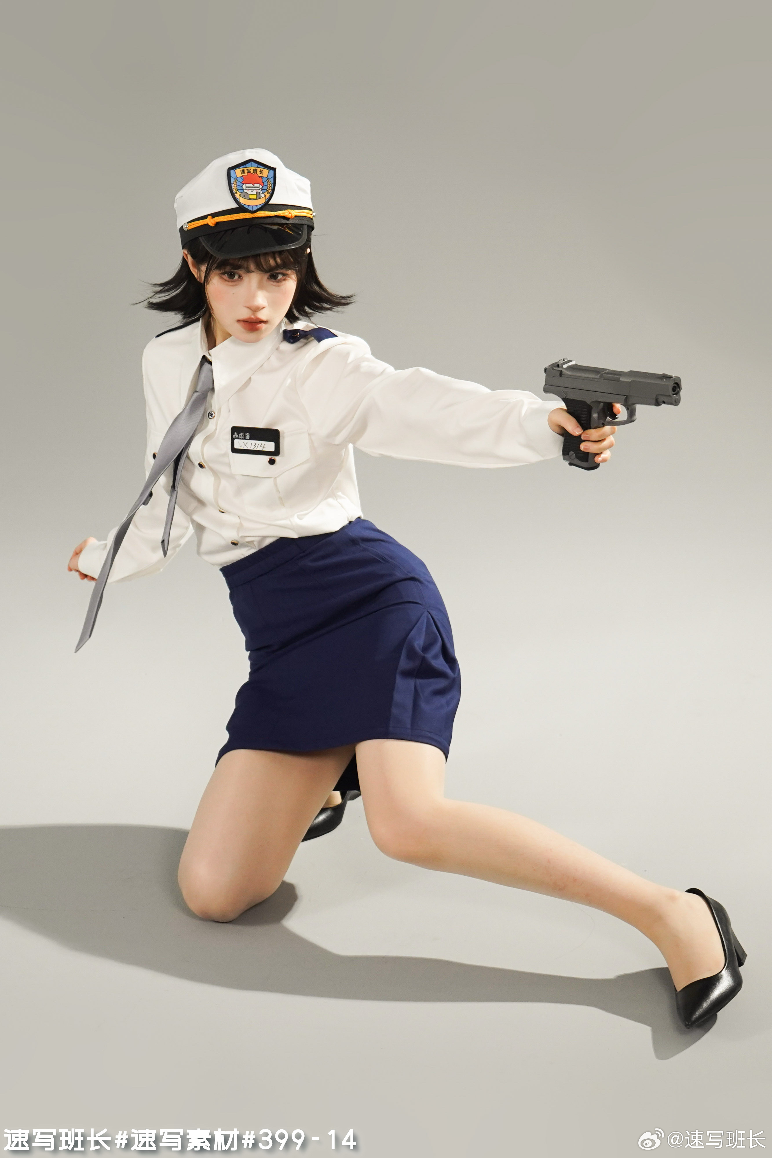 a full shot of a young asian woman dressed in a police officer's uniform, which includes a white shirt, dark blue skirt, and a captain's hat. she is holding a gun in her right hand, aimed towards the viewer. the woman is kneeling on the floor of a light grey studio. her gaze is focused ahead.